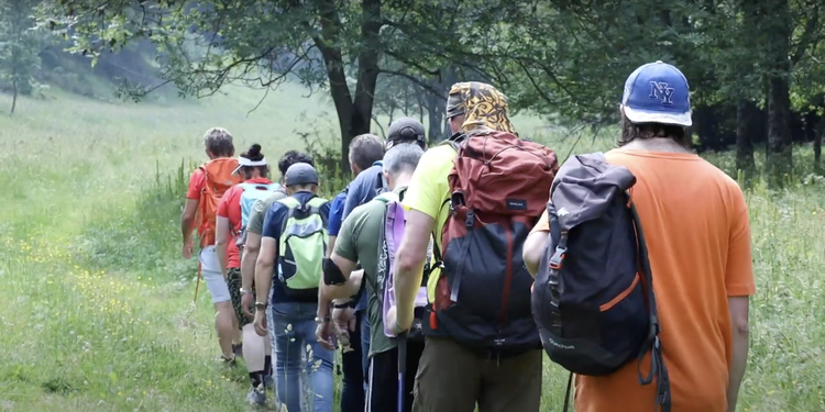 Escursionisti camminano in montagna in fila indiana. Ripresi di schiena